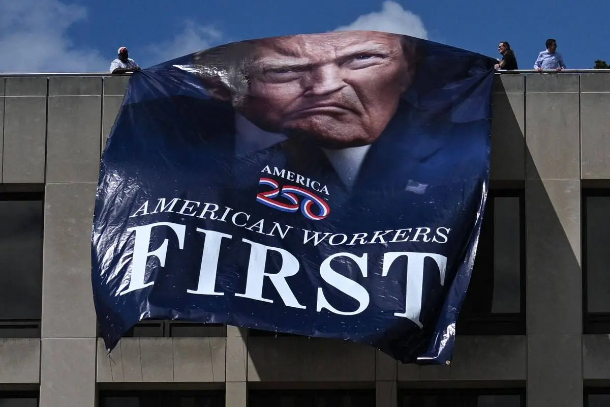 Cartaz com o rosto do presidente dos EUA, Donald Trump, é pendurado por funcionários do governo em Washington - Foto: reprodução/AFP
