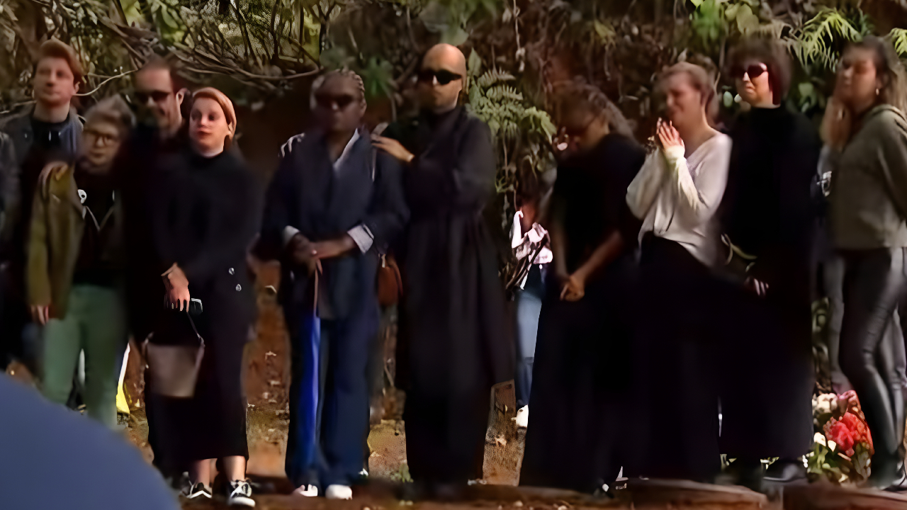 Integrantes do grupo Rouge prestam solidariedade à amiga. Algumas usam óculos escuros e usam roupas de tom escuro.