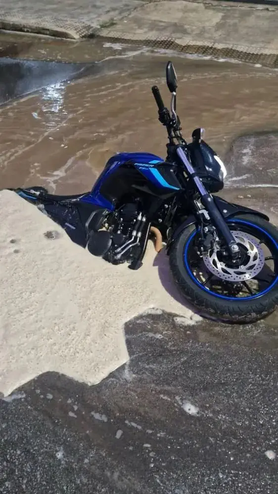 Motociclista tem moto submersa após afundamento de rua em Colatina; ele não se feriu. Foto: Divulgação.