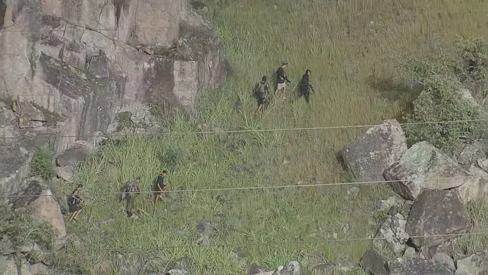 Em fila indiana, durante operação da PM, bandidos com fuzis fogem para a área de mata do Morro do Fubá, no Campinho — Foto: reprodução /TV Globo