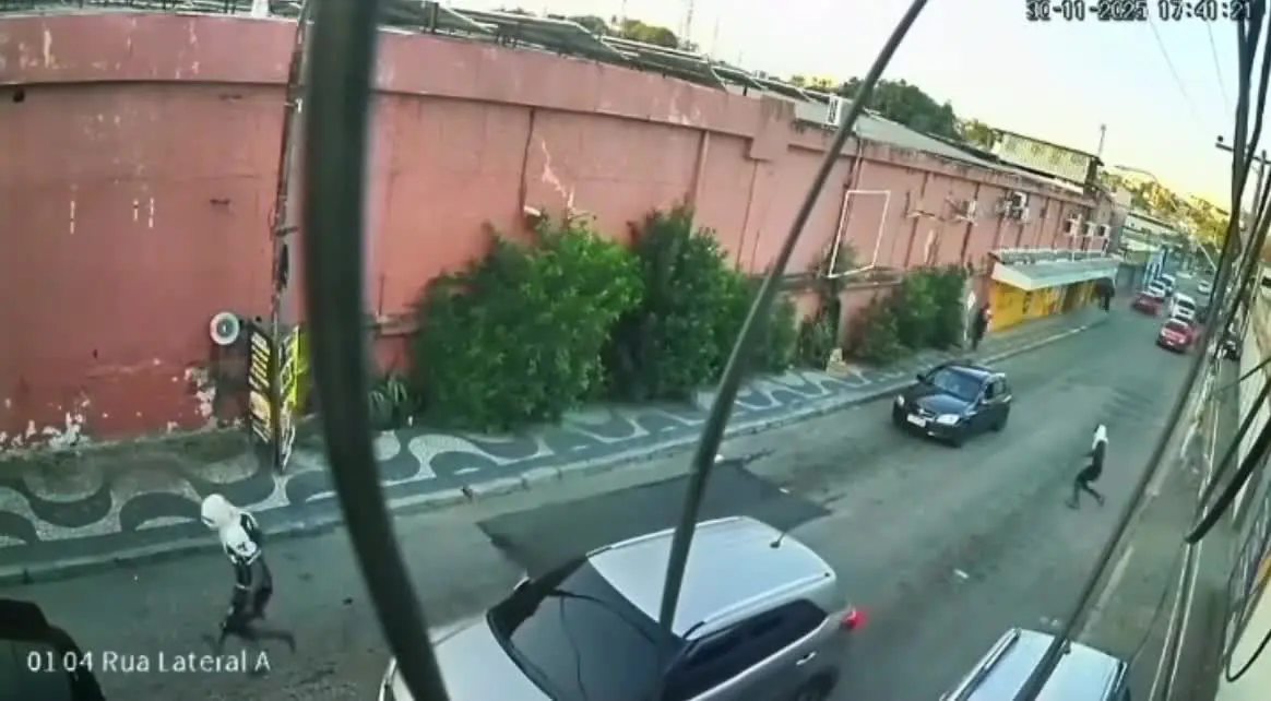 Um dos bandidos aparece pulando em uma perna só enquanto aponta um fuzil e aborda a vítima no meio da rua. Foto: Reprodução.