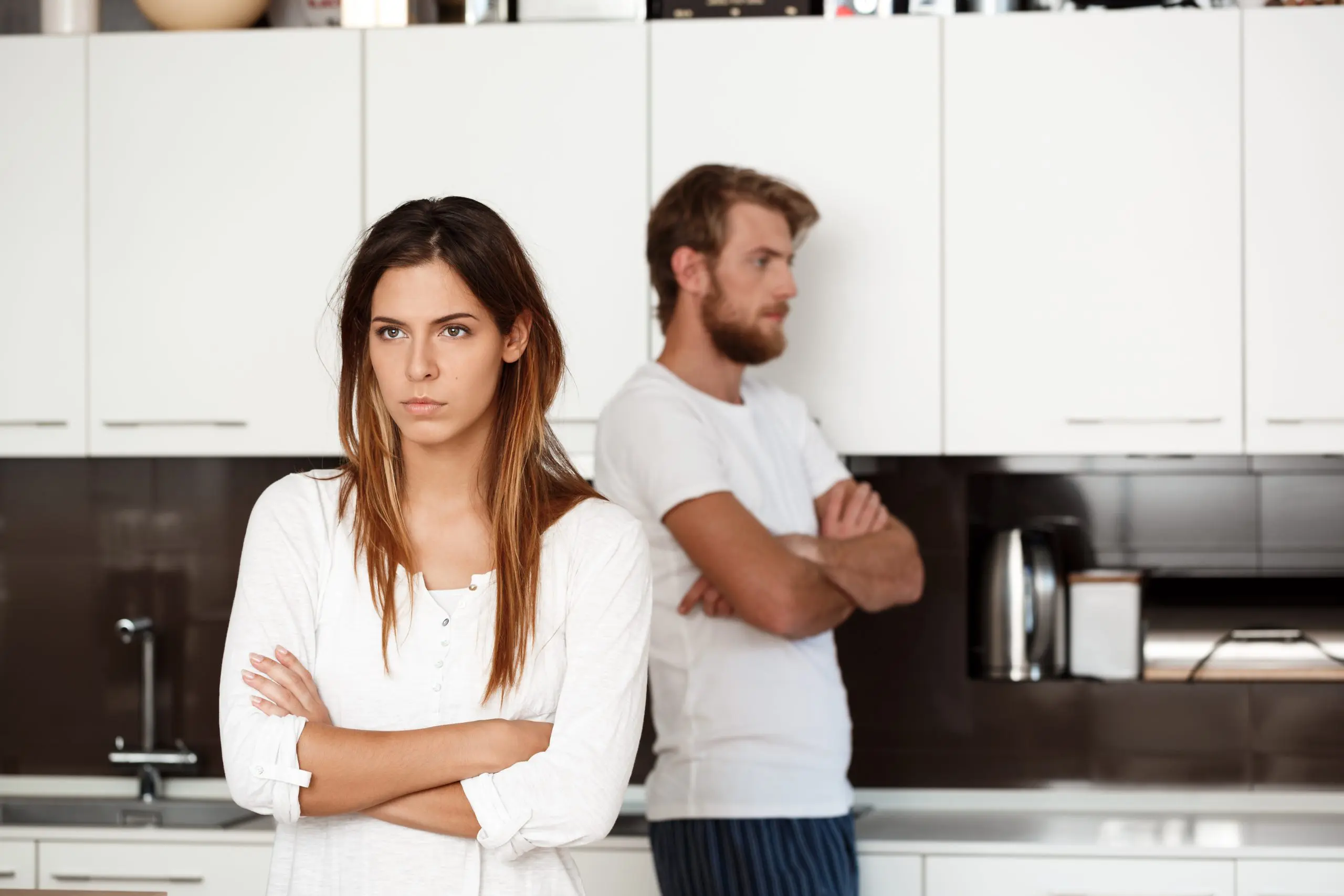 Displeased young beautiful brunette girl in quarrel with her boyfriend background at home.